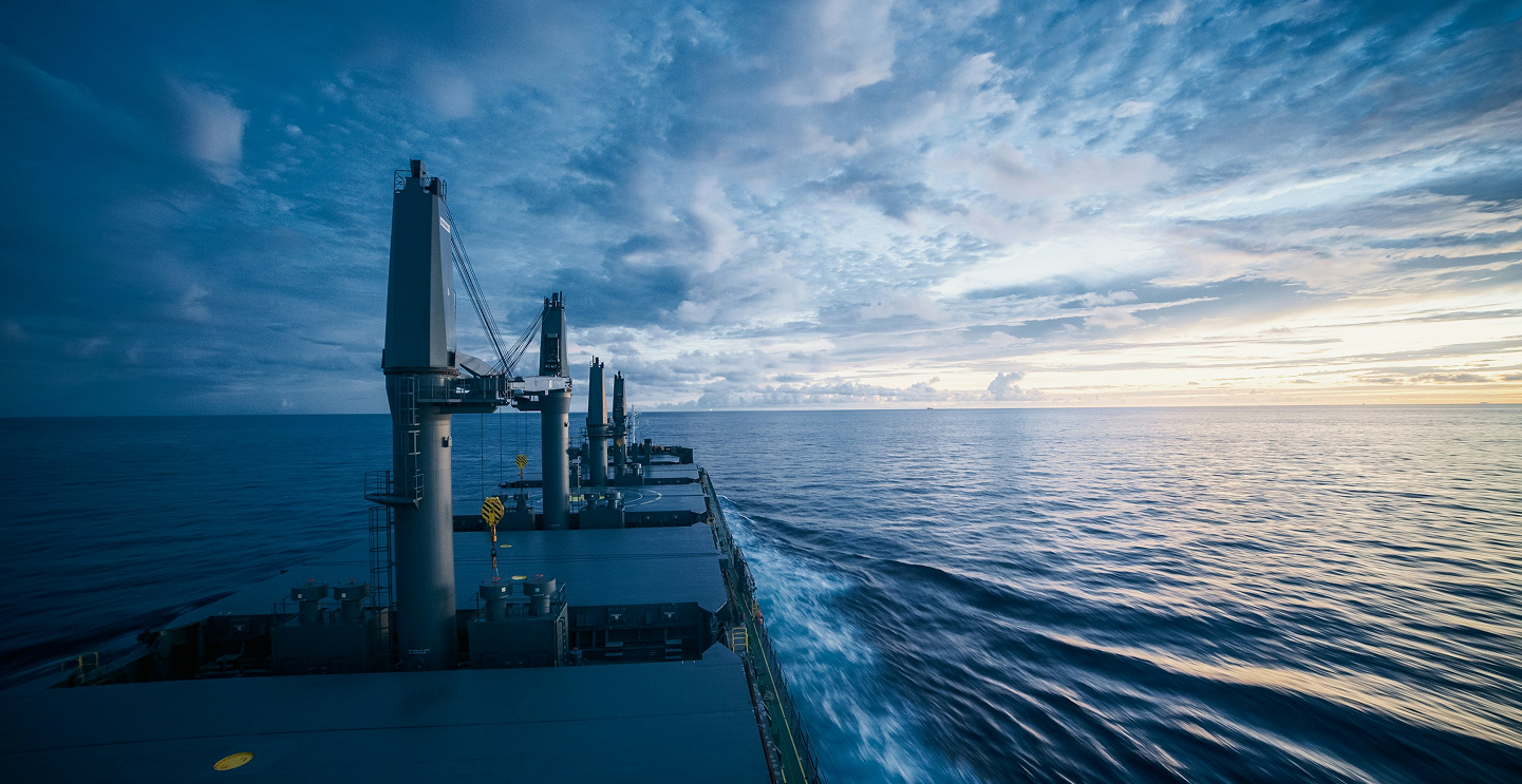 Cargo ship sailing across the open ocean at dusk